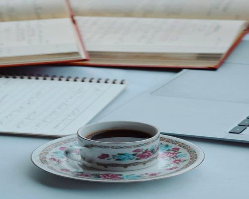 A cup of coffee next to an open notebook, suggesting a break from work