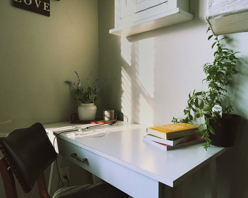 A desk placed perpendicular to a window with soft natural light streaming in